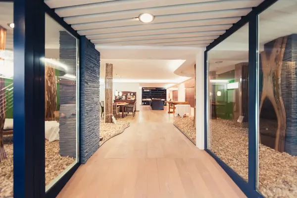 Moderner Hoteleingang mit Glaswänden, Holzfußboden und stilvollem Restaurantbereich.