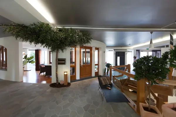 Modernes Hotellobby-Interieur mit viel Tageslicht, Pflanzen und gemütlichen Sitzbereichen.